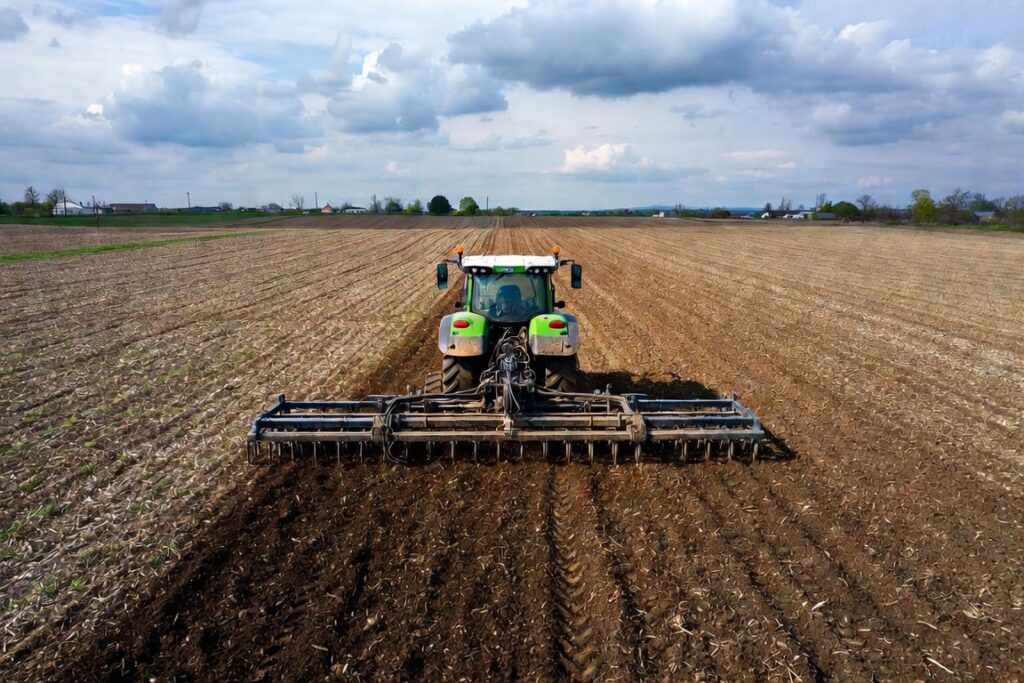 Tractor care pregătește solul pentru culturile de primăvară pe un teren agricol din România